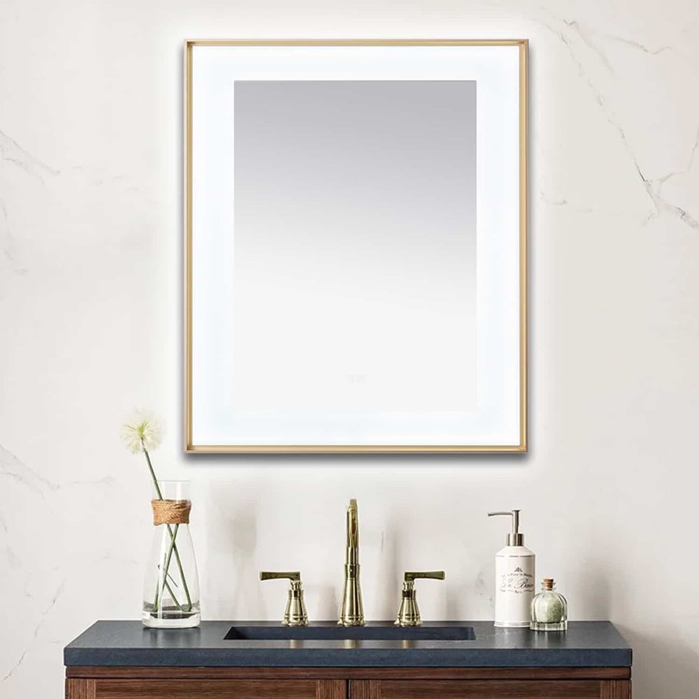 A bathroom vanity with a dark countertop, gold faucet, soap dispenser, and a single flower in a vase sits below the Lexington 30 inch x 36 inch LED Lighted Slim Frame Mirror on a light marble wall.