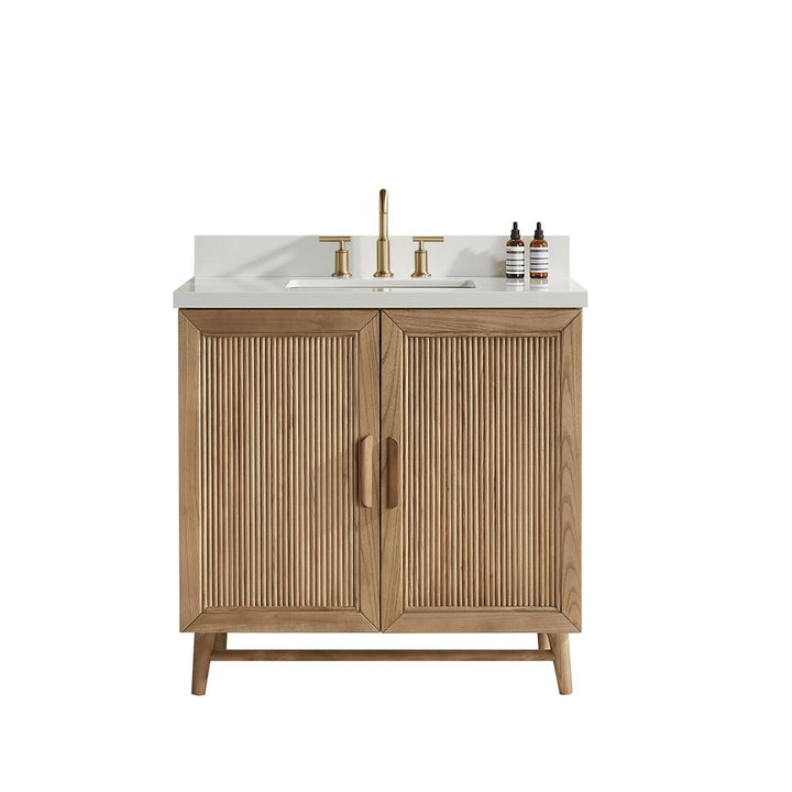 The Liora 30 Inch Bathroom Vanity features vertical slatted wooden cabinet doors, a white countertop with a gold faucet, and two small bottles on the right side of the sink, all set against a plain white background.