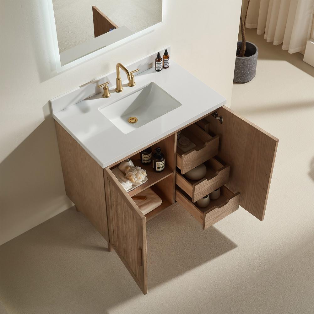 The Liora 30 Inch Bathroom Vanity features a white sink, gold faucet, and open wooden cabinet doors revealing organized shelves and drawers for towels, bottles, and containers, all set on a light-colored floor.