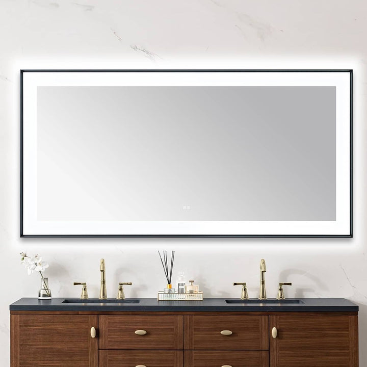 A modern bathroom features the Lexington 72 inch x 36 inch LED Lighted Slim Frame Mirror above a double sink vanity with brass faucets, wooden cabinets, and toiletries neatly arranged on the countertop.
