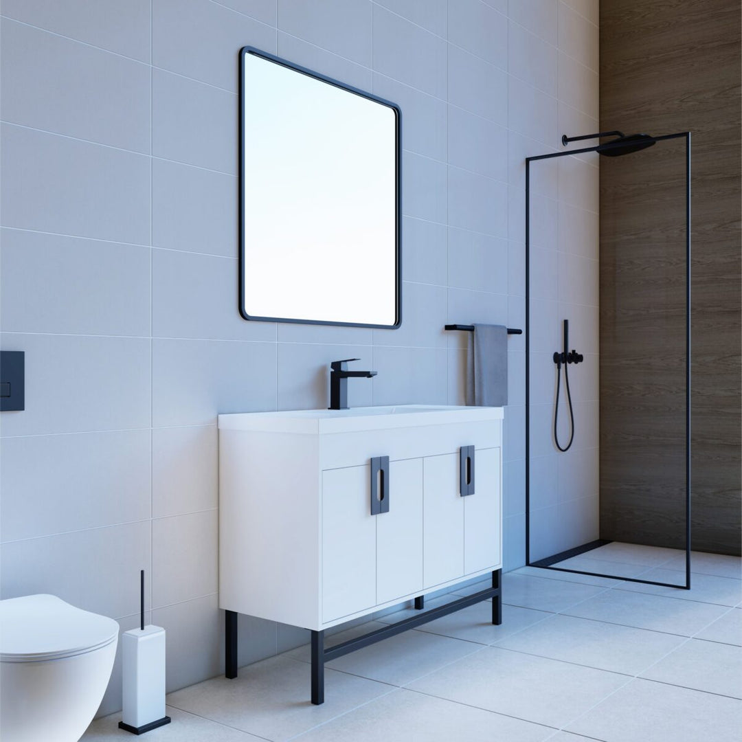 A modern bathroom features a Salento 48 Single Bathroom Vanity in White with sink, sleek black hardware, a square mirror, and a glass-door shower with black framing. Light tiles and minimalistic decor add to the elegant ambiance.