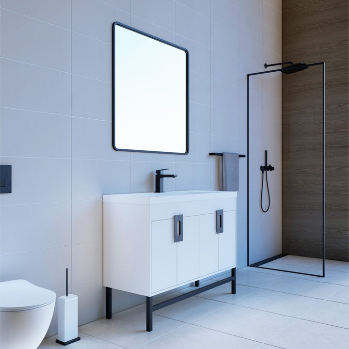 A modern bathroom features a Salento 48 Single Bathroom Vanity in White with sink, sleek black hardware, a square mirror, and a glass-door shower with black framing. Light tiles and minimalistic decor add to the elegant ambiance.