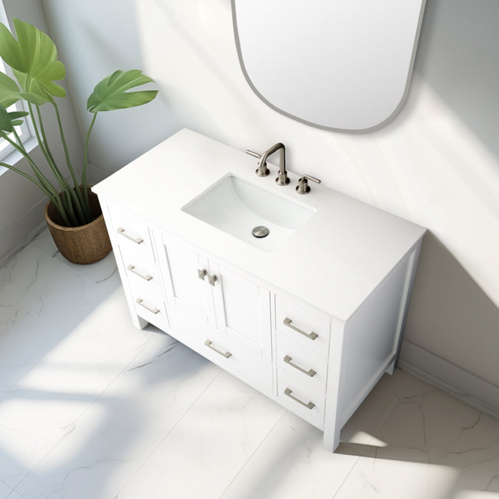 A Vanea 48 inch Bathroom Vanity in White with a white quartz top stands against a white wall beside a large green potted plant as sunlight streams through the window onto the tiled floor.