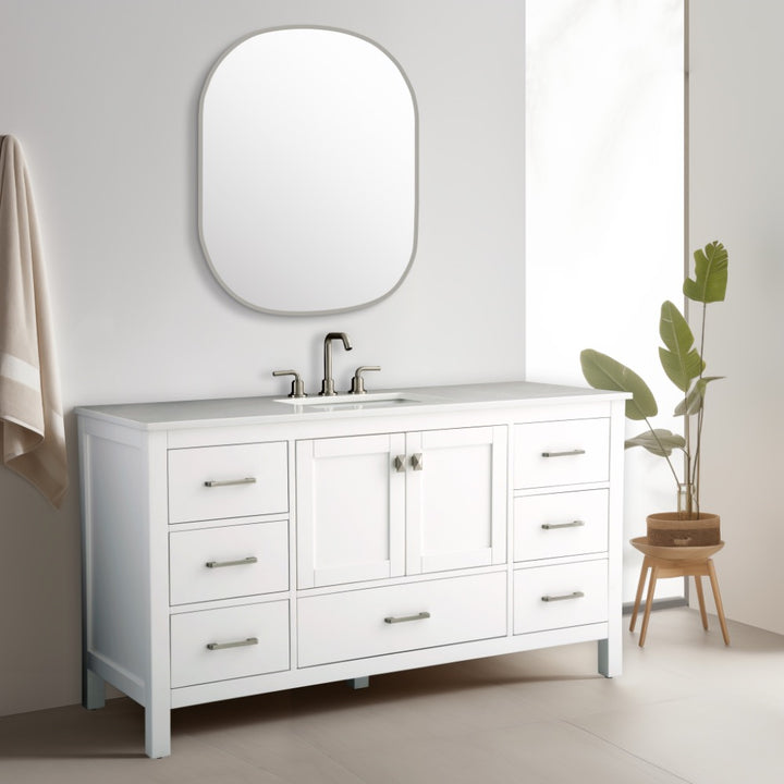 Modern bathroom with a Vanea 60 inch Single Bathroom Vanity in White with White Quartz Top, featuring six drawers, two cabinets, rectangular countertop and silver faucet, large oval mirror above, beige towel on the wall, and potted plant on wooden stand.