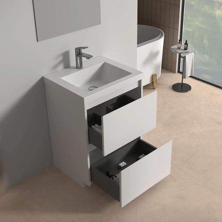 The Arvia 24 inch Bathroom Vanity with Sink features two open drawers holding toiletries, a square sink with a chrome faucet, and is set in a bathroom with a bathtub, small round table, and large window in the background.