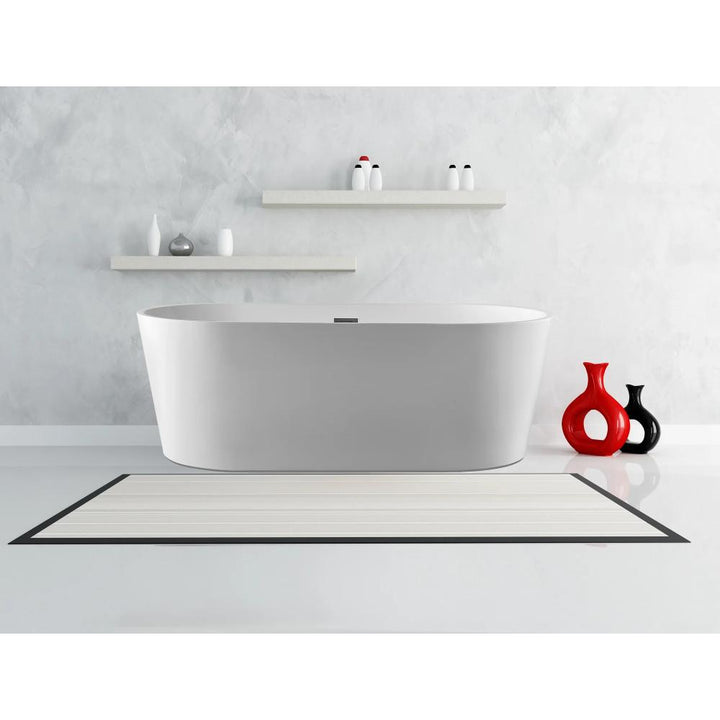 A modern bathroom features the Luma Freestanding Bathtub, a pale rug, two floating shelves with decorative bottles, and red vases on the floor, all set against a light gray wall.