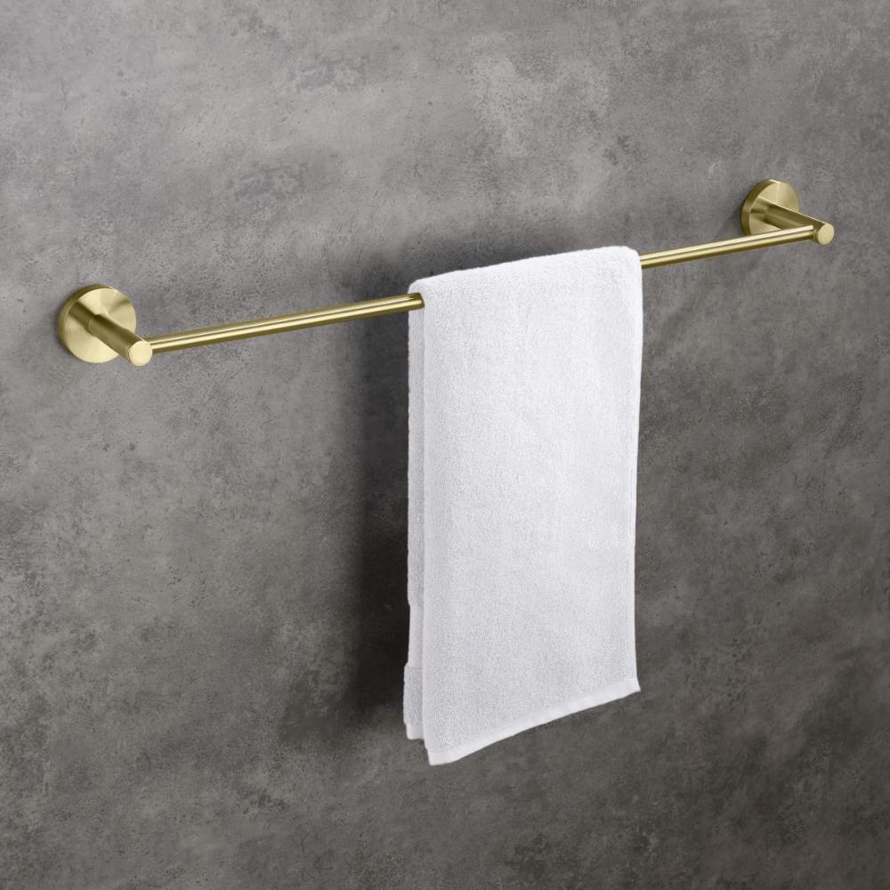 A white towel hangs neatly on a gold-colored towel bar mounted on a gray, textured wall.