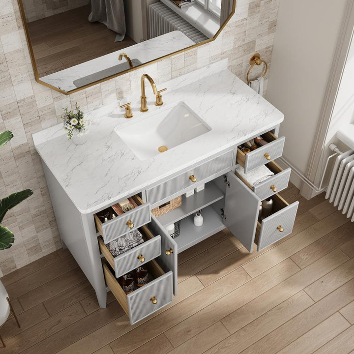The Aveline 48 Inch Freestanding Bathroom Vanity With Top features a white marble countertop, gold faucet, rectangular sink, six open drawers for toiletries, plus a mirror, vase with flowers, and towel ring for an elegant touch.