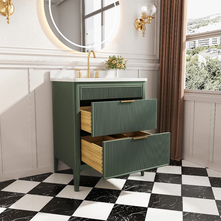 A modern bathroom with an Aveline 30 Inch Freestanding Bathroom Vanity With Top, two open drawers, gold faucet, circular mirror, wall sconces, checkered floor, and a window with brown curtains and an outdoor view.