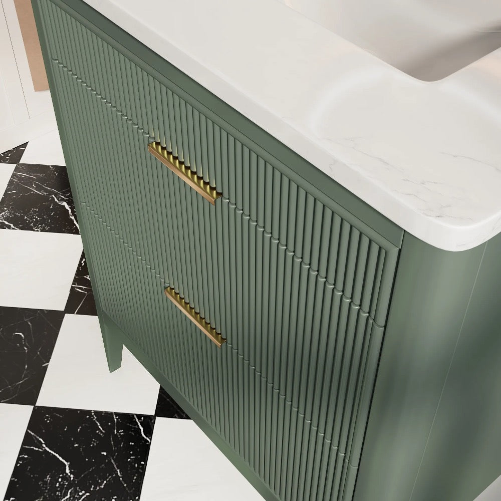 The Aveline 30 Inch Freestanding Bathroom Vanity With Top showcases a green finish with vertical grooves, gold handles, and a white marble countertop, pairing perfectly with a black and white checkerboard tile floor.