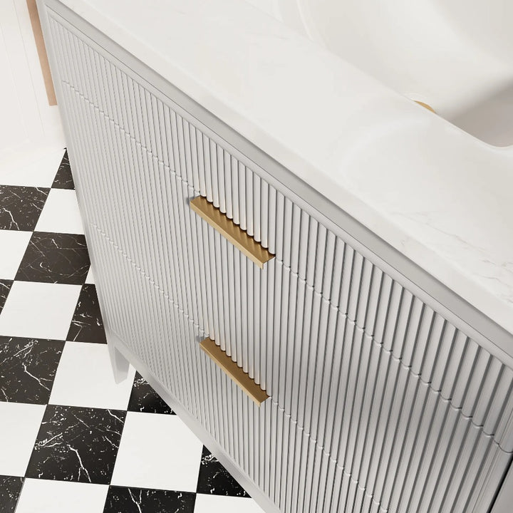 The Aveline 36 Inch Freestanding Bathroom Vanity With Top features vertical ridges, gold handles, and a white marble countertop, and is shown on a striking black and white checkered tile floor.
