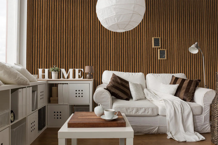 A cozy living room with a white sofa, brown and white cushions, a blanket, a small coffee table with tea set, “HOME” letters, modern shelving, and the Acoustic Interior Wall Panel as an elegant accent.