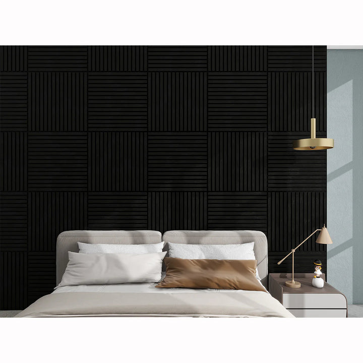 A modern bedroom features a beige bed with pillows, a side table and lamp, and the Acoustic Interior Wall Panel with a geometric grid of square panels. A gold pendant light above adds elegance to the space.