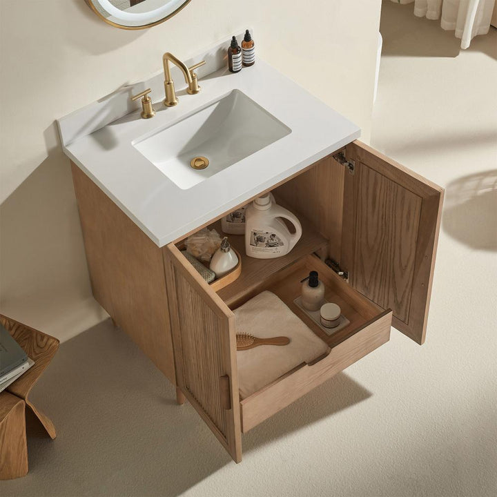 The Liora 36 Inch Bathroom Vanity showcases a white sink, gold faucet, and open wooden doors with organized essentials inside, all in a light neutral palette for a serene bathroom look.
