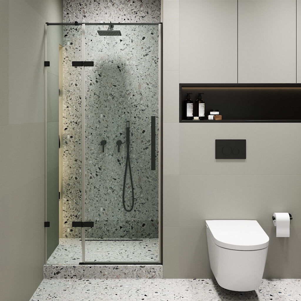 Modern bathroom with a Nova Hinged Frameless Shower Door, terrazzo walls and floor, wall-mounted showerhead, black fixtures, a wall-mounted toilet to the right, toilet paper holder, and shelf with toiletries.