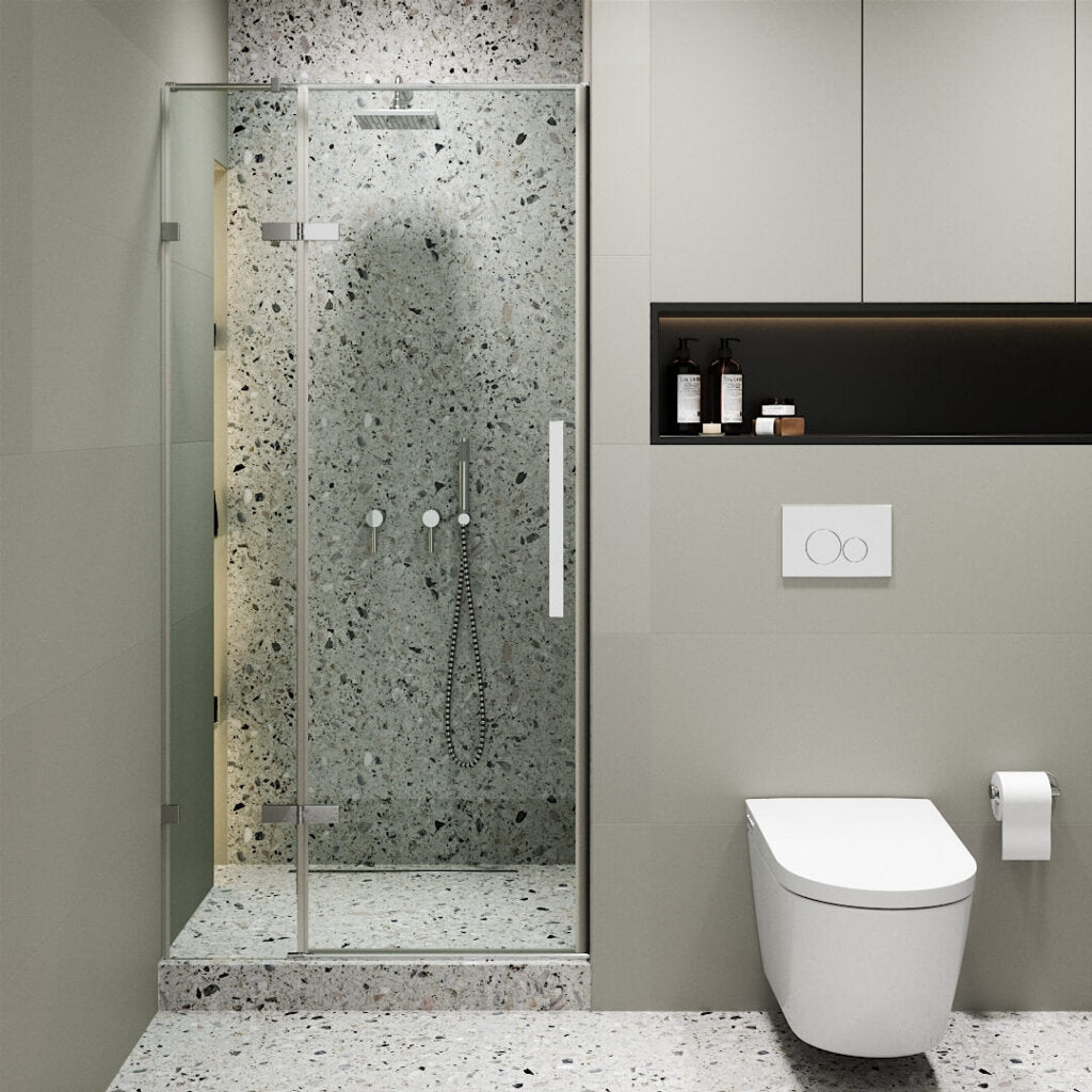 Modern bathroom with a Nova Hinged Frameless Shower Door enclosing terrazzo walls and floor, wall-mounted toilet, toilet paper holder, recessed shelf with toiletries, and neutral-toned walls and cabinetry.