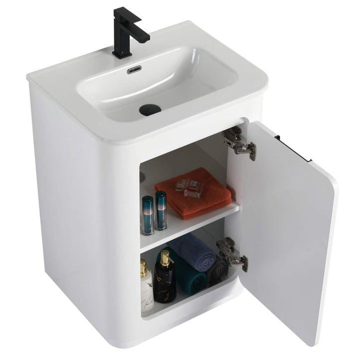 The Shireplace 24 Inch Bathroom Vanity features a sleek white finish, an open cabinet door revealing two shelves for toiletries, and is completed with a striking black faucet for a modern touch.