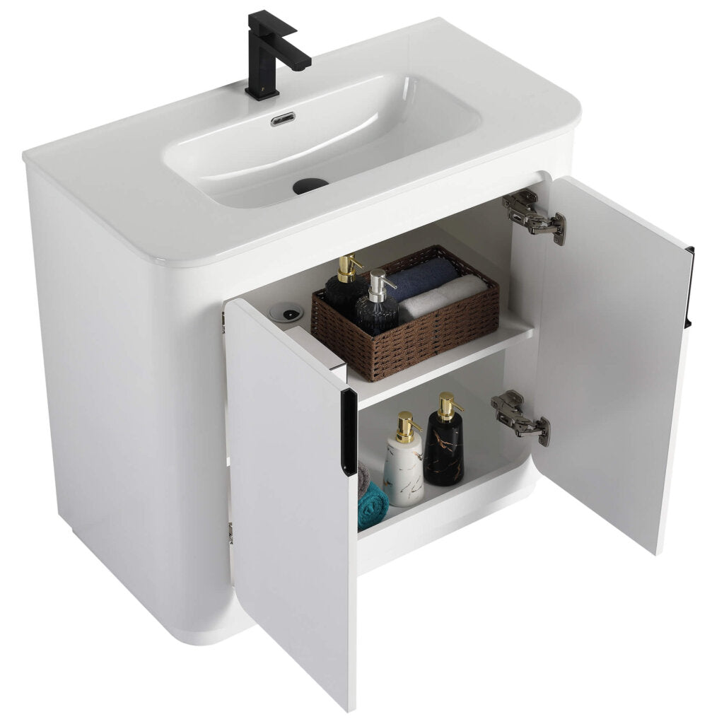 Introducing the Shireplace 36 Inch Bathroom Vanity With Sink—this white beauty features a built-in sink and stylish black faucet. Behind its cabinet doors, discover a shelf with a chic brown basket, bottles, and neatly folded towels. It embodies modern minimalism at its finest.