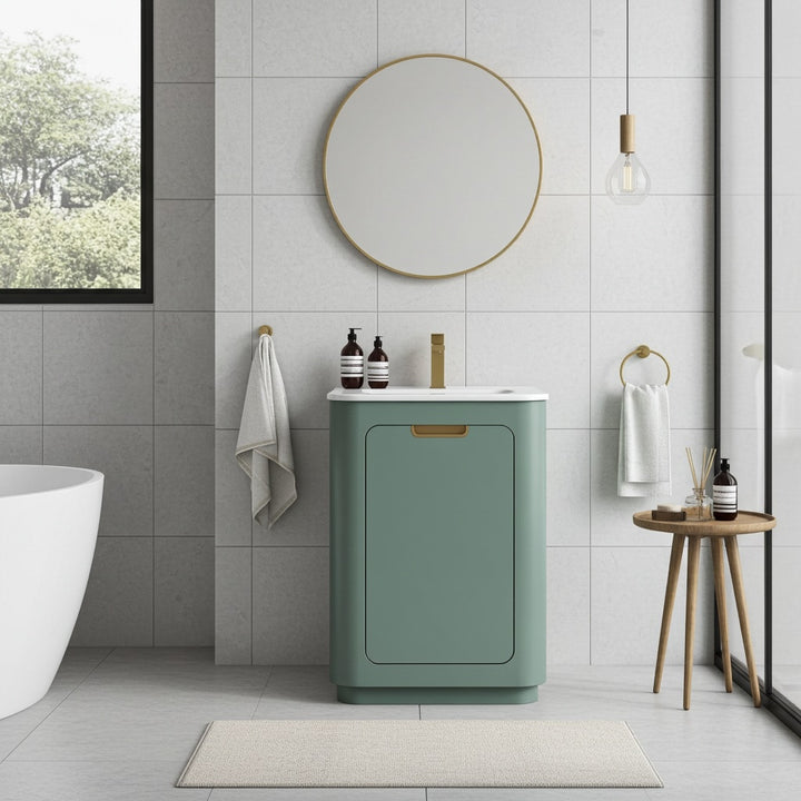 A modern bathroom features the Shireplace 24 Inch Bathroom Vanity With Sink, a round mirror, gold-accented green vanity, hanging towel, soap dispensers, stool with toiletries, bathtub, and a large window with greenery views.