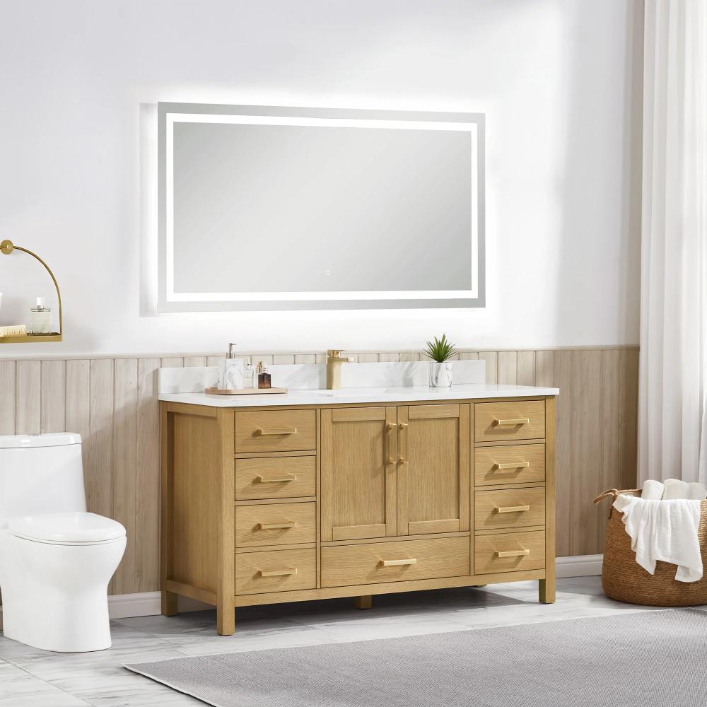 A modern bathroom featuring the Basel 60 Inch Single Bathroom Vanity, a double sink, large rectangular backlit mirror, white toilet, gold faucet, and a wicker basket with towels beside a window dressed in white curtains.