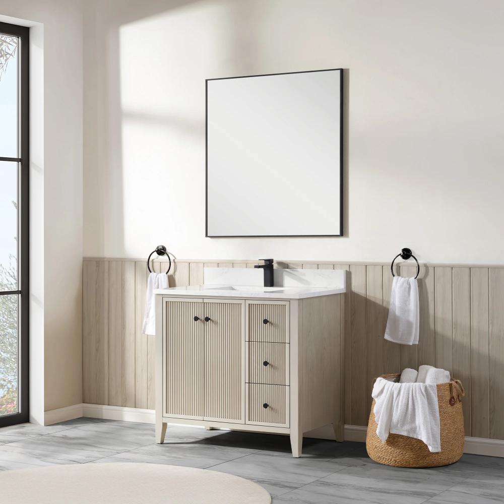 A modern bathroom features the Torino 36 Inch Bathroom Vanity Cabinet with drawers, black faucet, square mirror, towel rings with white towels, and a woven basket on a gray tile floor. Sunlight streams in from a large window.