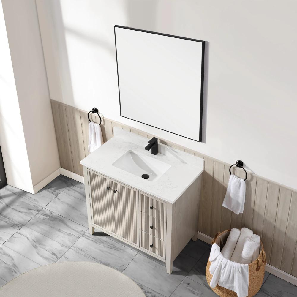 A modern bathroom features the Torino 36 Inch Bathroom Vanity Cabinet with drawers, a white countertop and sink, black faucet, large square mirror, towel rings with white towels, and a basket of rolled towels on gray tile flooring.