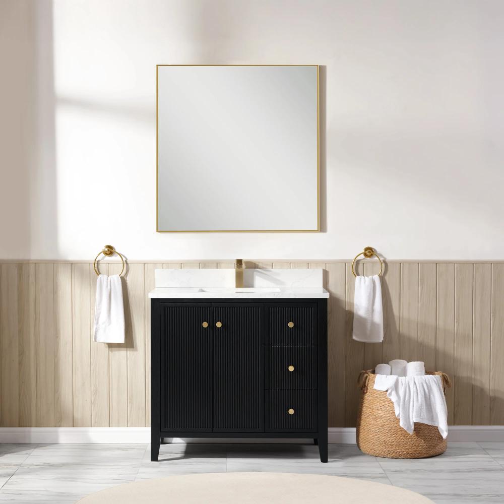 A modern bathroom showcases the Torino 36 Inch Bathroom Vanity Cabinet with drawers, a square gold-framed mirror above, a white sink, gold-accented hardware, two towel rings with white towels, and a wicker basket of rolled towels on the floor.