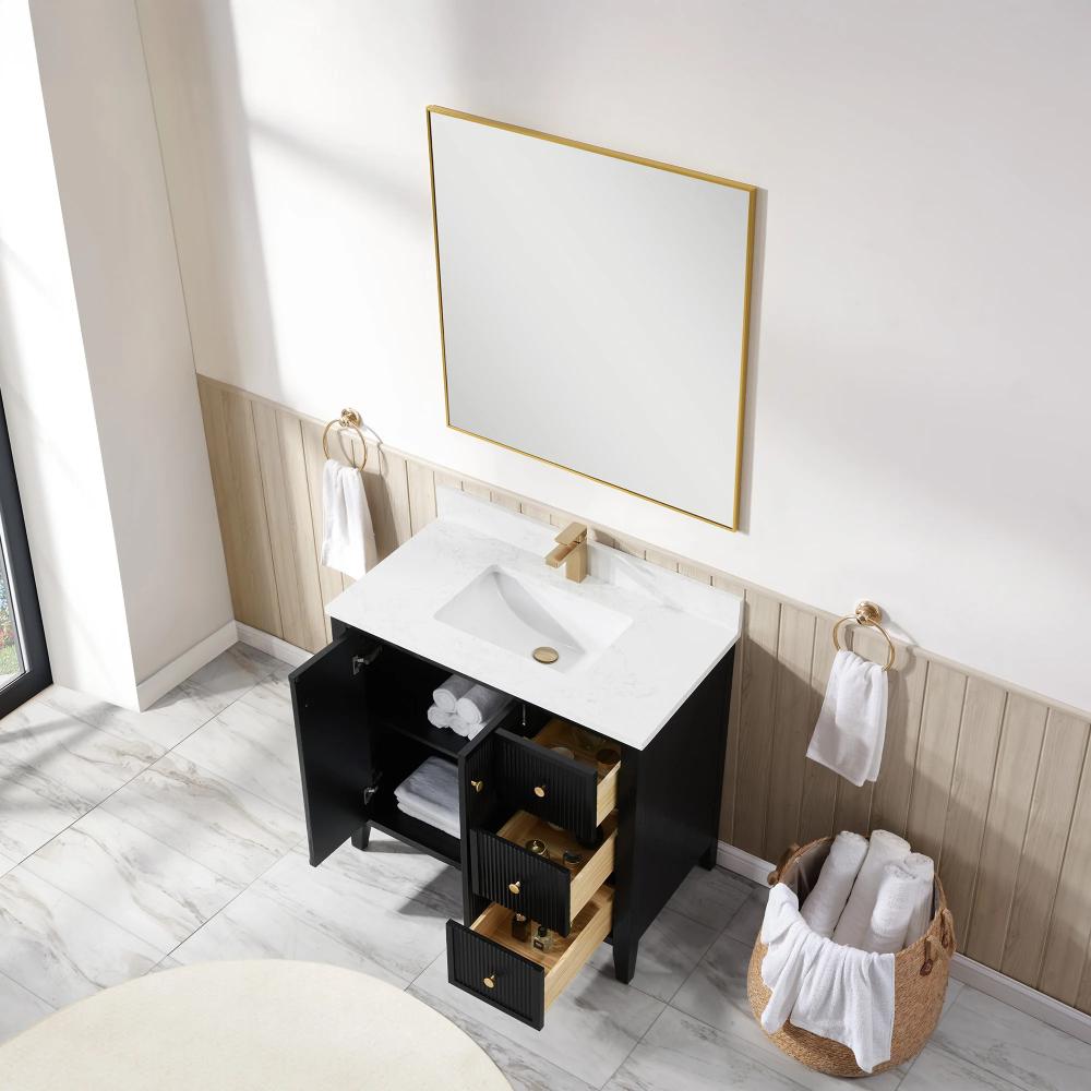 A modern bathroom features the Torino 36 Inch Bathroom Vanity Cabinet with drawers, a white countertop, black finish, and gold faucet. The open cabinet displays towels and toiletries. Nearby are a large mirror, towel rings, and a basket with rolled towels.