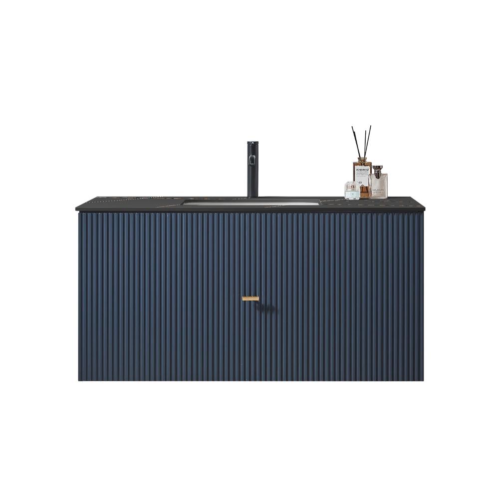 The Barcelona 42 Inch Wall Mount Bathroom Vanity in navy blue features fluted details, a black countertop and faucet, gold handle, and is styled with a glass jar and reed diffuser on the right side.