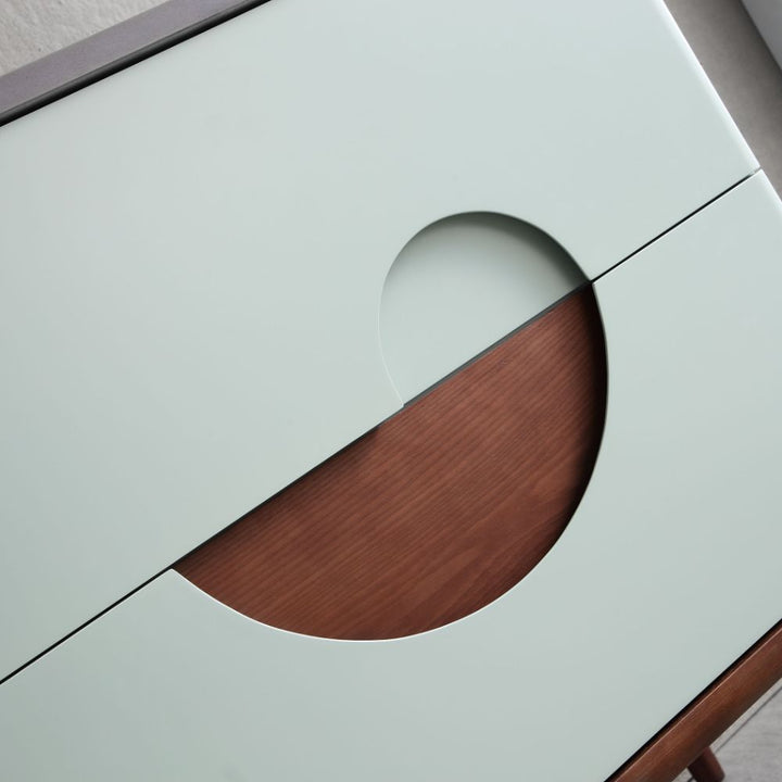 A close-up of the Burano 30 inch Aloe Green Freestanding Bathroom Vanity shows light green panels with a circular cutout revealing wood beneath, creating a modern, geometric look.