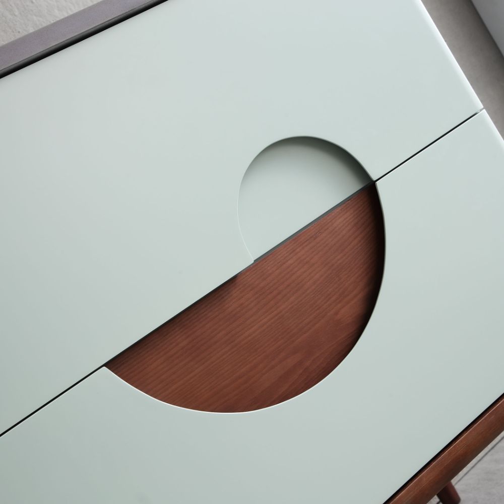 A close-up of the Burano 48 inch Aloe Green Freestanding Bathroom Vanity shows its geometric design, with two partially opened pale green doors revealing a circular cut-out pattern over a brown wooden surface.