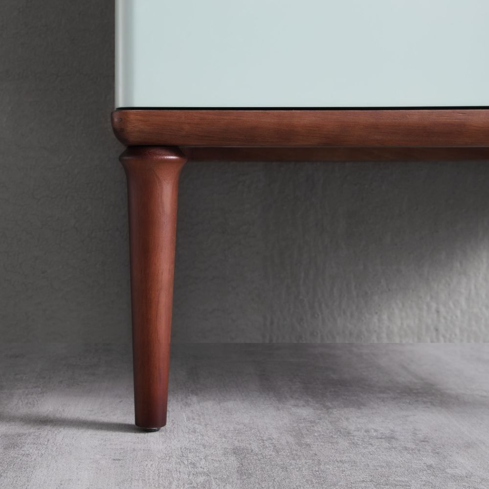 Close-up of the lower corner of the Burano 48 inch Aloe Green Freestanding Bathroom Vanity with tapered legs and a smooth, light front against a textured gray wall and floor.