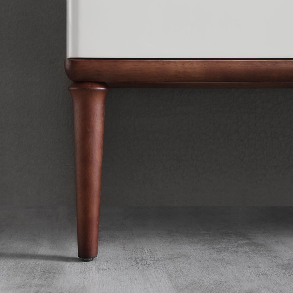 Close-up of the bottom corner of the Burano 30 inch Beige Freestanding Bathroom Vanity with a dark wooden leg, set against a gray textured wall and gray wood floor.