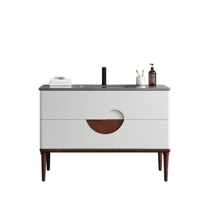 The Burano 48 inch Beige Freestanding Bathroom Vanity features a beige front, wooden legs, black countertop and faucet, plus stylish accessories like folded towels, a soap dispenser, and a toothbrush holder.