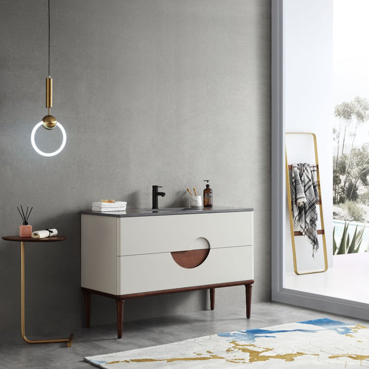 Modern bathroom with the Burano 48 inch Beige Freestanding Bathroom Vanity, round pendant light, small side table and decor, large window reflecting trees, a blanket on the standing mirror, and a patterned rug completing the look.