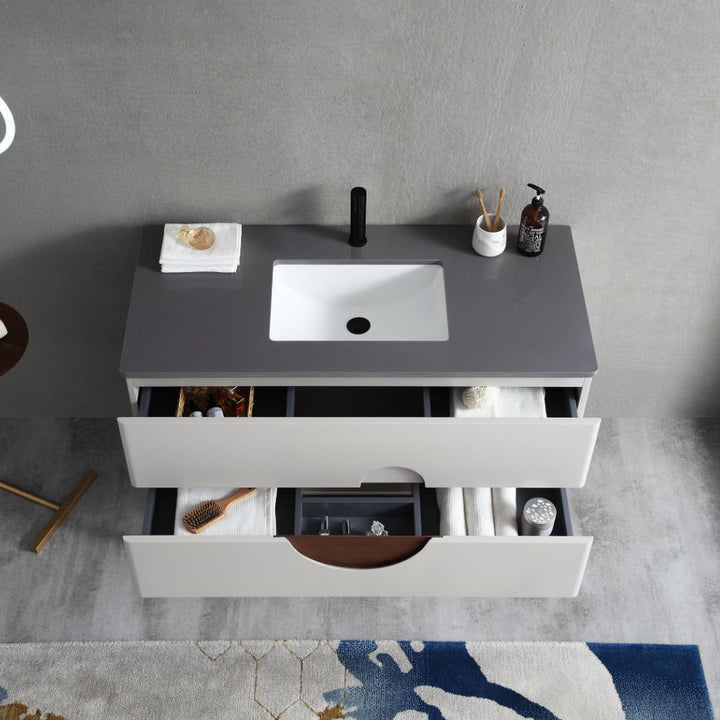 The Burano 48 inch Beige Freestanding Bathroom Vanity features a gray countertop, white sink, black faucet, soap dispenser, toothbrush holder, plus two drawers for towels and toiletries. A rug and stool are partially visible below.