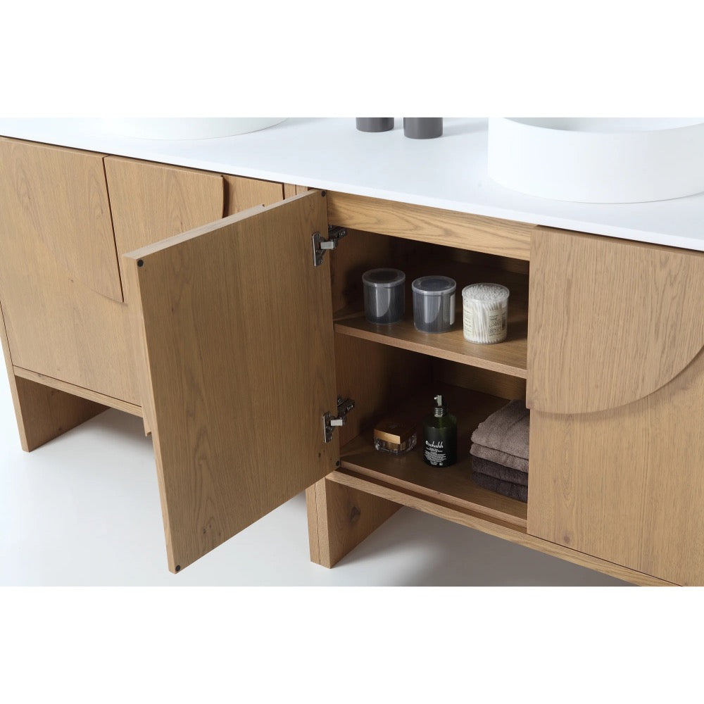 The Celle 72 Inch Double Bathroom Vanity With Vessel Sinks features open doors revealing shelves with two clear containers, a small towel, a green bottle, a candle, and a small box beneath a white countertop with dual sinks.
