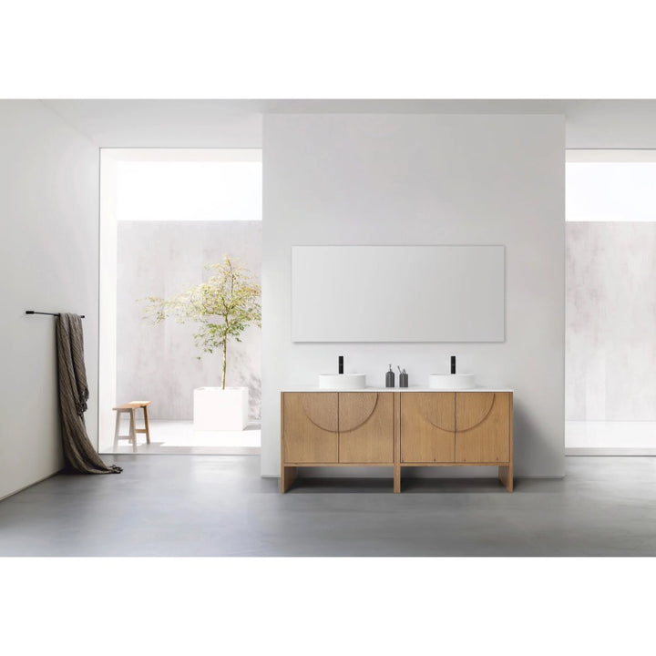 Minimalist bathroom with a Celle 72 Inch Double Bathroom Vanity With Vessel Sinks, black faucets, and a large mirror. A towel hangs on the left wall as natural light enters through a window showcasing a potted tree outside.