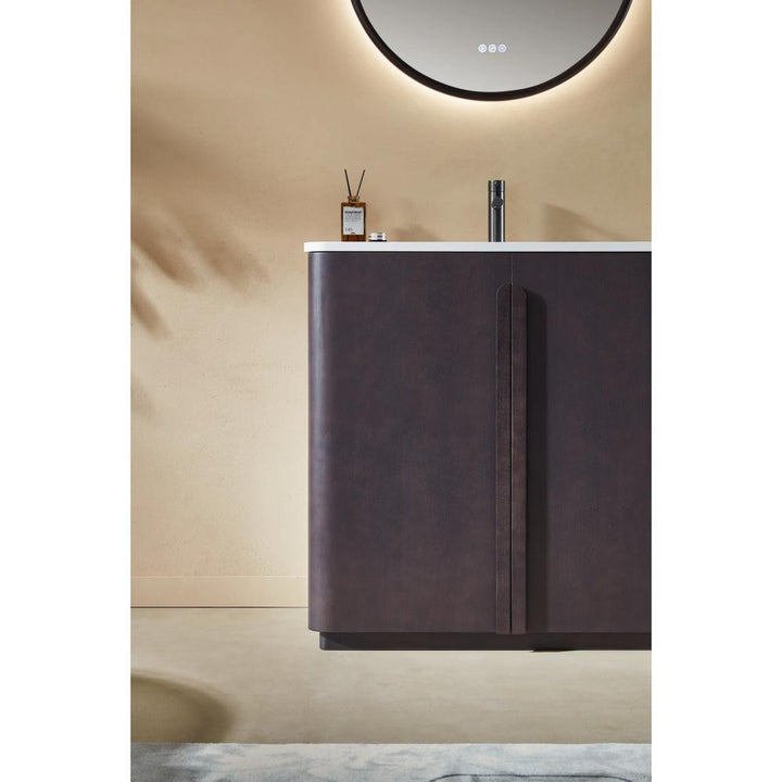 The Parma 36 Inch Bathroom Vanity With Top showcases a dark brown cabinet, white countertop, illuminated round mirror above, and small accessories on the counter against a beige wall.