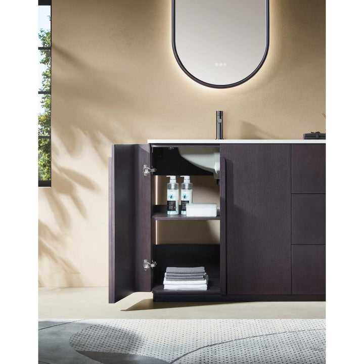 The Parma 48 Inch Bathroom Vanity With Top features dark wood cabinets and a door opening to shelves with towels and bottles, set beneath a curved, softly backlit mirror. A window and part of a patterned rug are also visible.