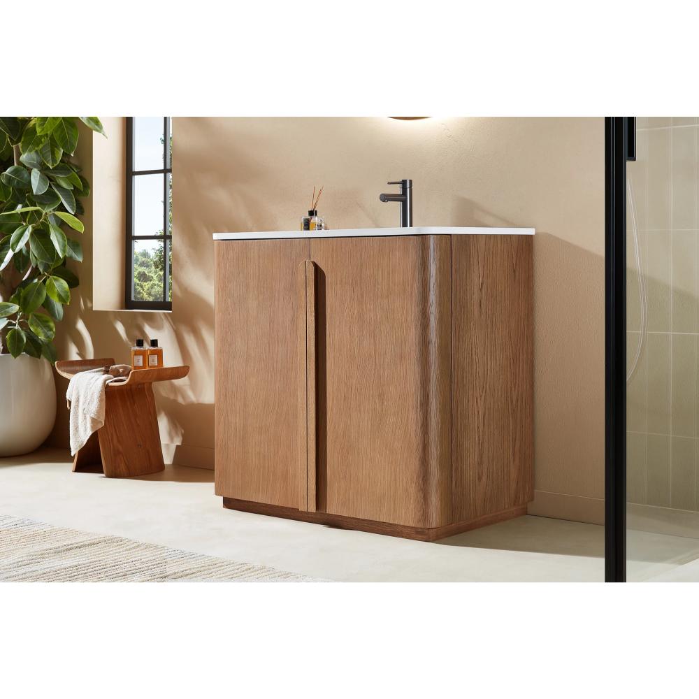 A modern bathroom showcases the Parma 36 Inch Bathroom Vanity With Top, featuring a wooden cabinet, white countertop, black faucet, and decor. A plant, wooden stool with toiletries, and a window add to the serene atmosphere.