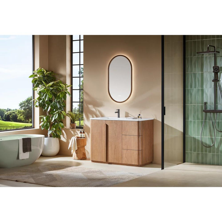 Modern bathroom featuring a Parma 48 Inch Bathroom Vanity With Top, an oval backlit mirror, large potted plant, freestanding bathtub, glass shower, and tall windows that bathe the space in natural light.