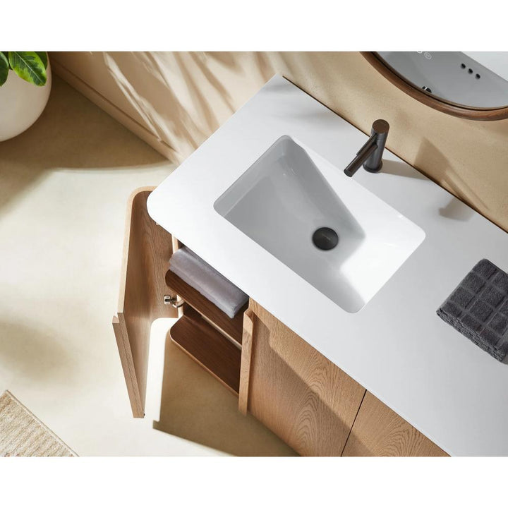 The Parma 72 Inch Double Bathroom Vanity With Top features dual white rectangular sinks, black faucets, a wooden cabinet with open shelves and rolled towels inside. Folded dark towels and a green plant on the countertop add freshness.