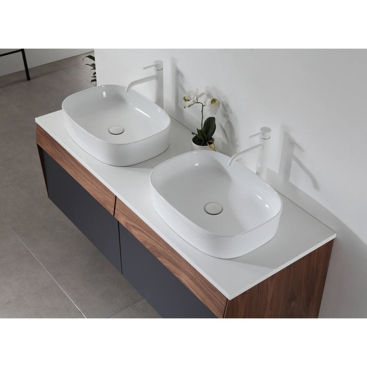 The Ronda 55 Inch Wall Mount Vanity with Double Vessel Sinks showcases a modern white countertop, two rectangular vessel sinks, white faucets, a decorative orchid plant, and stylish wood and dark gray cabinet doors.
