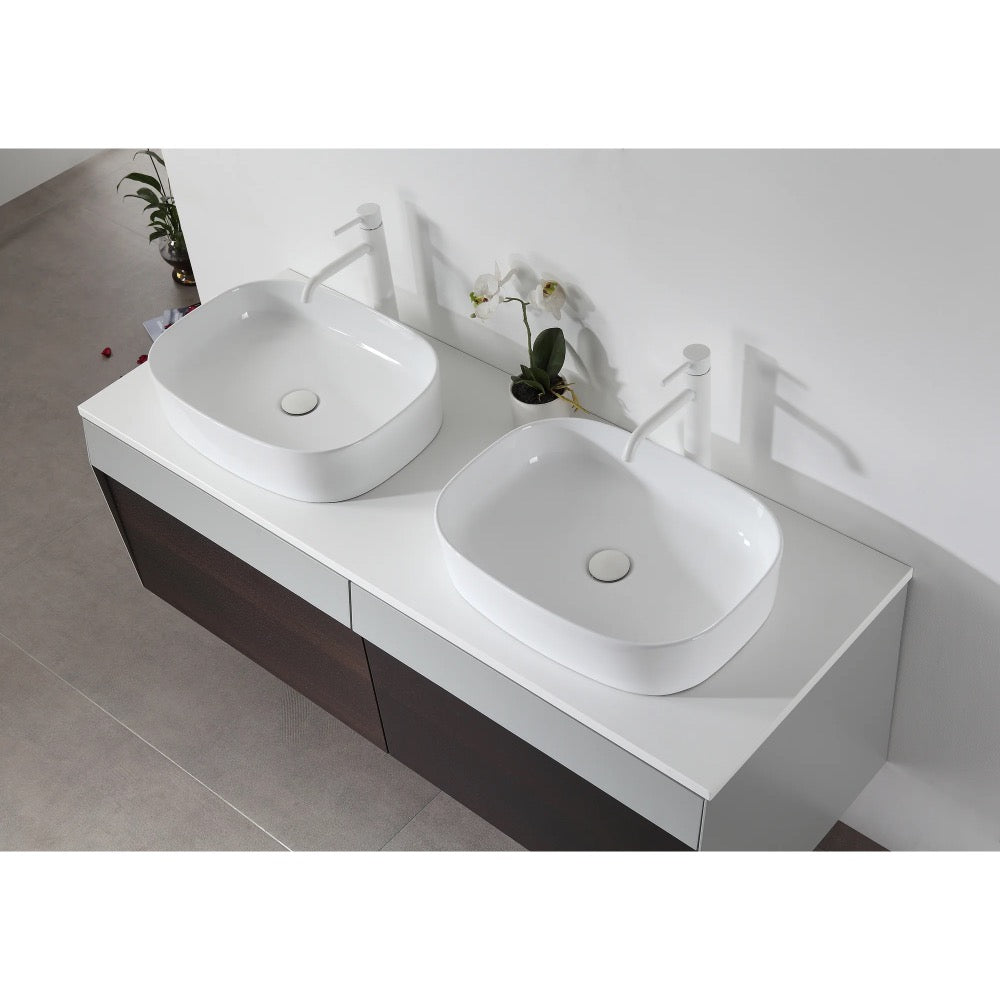 Overhead view of the Ronda 55 Inch Wall Mount Vanity with double vessel sinks, white faucets, a dark wood cabinet, and a small plant and orchid placed between the sinks.