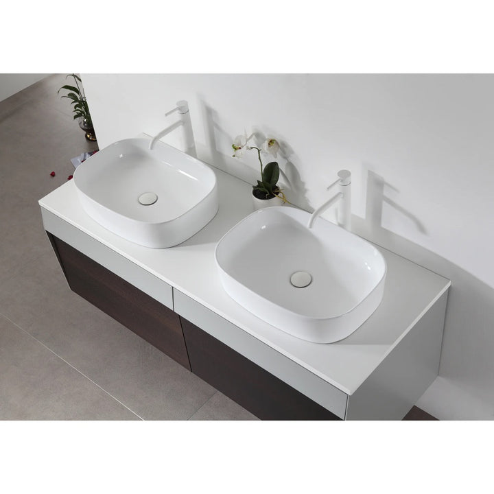 Overhead view of the Ronda 55 Inch Wall Mount Vanity with double vessel sinks, white faucets, a dark wood cabinet, and a small plant and orchid placed between the sinks.