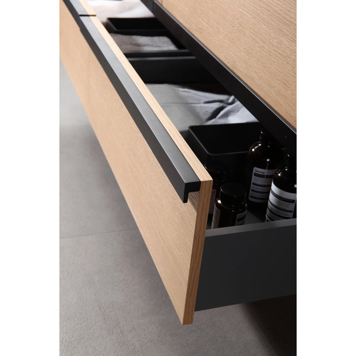 A close-up of a wooden drawer with a black handle reveals organized bottles and containers. The drawer is part of the Sintra 55 Inch Wall Mount Vanity with Double Vessel Sinks, seen on a tiled floor.
