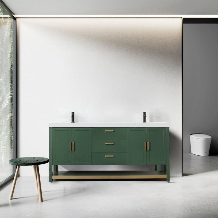 A modern bathroom showcases the Winchester 72 Forest Green Vanity with a white countertop and brass handles, flanked by two faucets. A round green stool with wooden legs is on the left by a large window, while a white toilet is secluded on the right behind a partial wall.